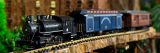 a clos up of a black model train on track with a blue and red car behind