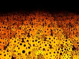 Luminescent orange pumpkin sculptures with black polka dots being reflected by mirrors.