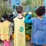 Three children's backs wearing hand made capes for being plant champions