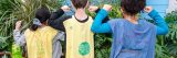 Three children's backs wearing hand made capes for being plant champions