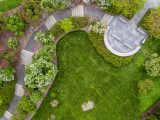 Overhead shot of a winding path with stairs with lilacs surrounding them and green grass