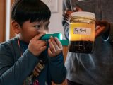 Boy with flashlight looking into a jar of top soil