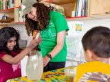 Staff and 2 students doing an activity with honey in a classroom