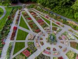 Aerial shot of Rose Garden showing grey pathways, green trees, and rose bushes of various shades of pink, red, orange and white.