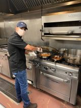 Constellation Culinary Group chef Ali Loukzada cooking at a stove.