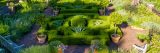 Aerial view of bright green bushes, brick pathway, potted trees, and wooden benches.