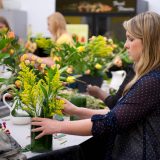 A student creating a flower arrangement with store-bought bouquets