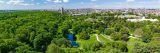 Panoramic image of the New York Botanical Garden with trees, and the conservatory in view and the outline of New York City in the back