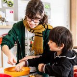 a woman and young boy dressed warmly stirring ingredients together