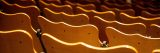 Backs of curved wooded low back chairs in an auditorium.