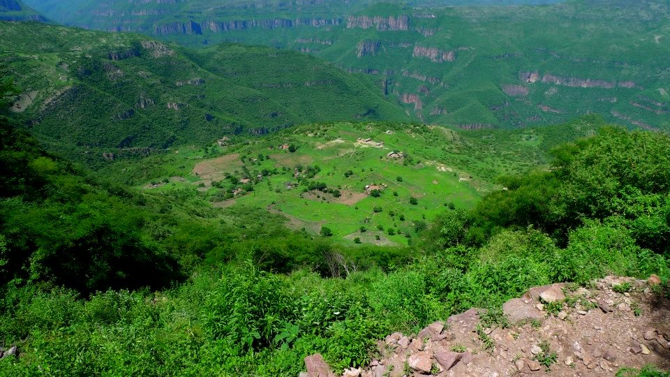 Photo from a distance of a small village among green mountains