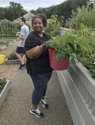 Sophia M. holding a bucket of harvested vegetables in the Edible Academy