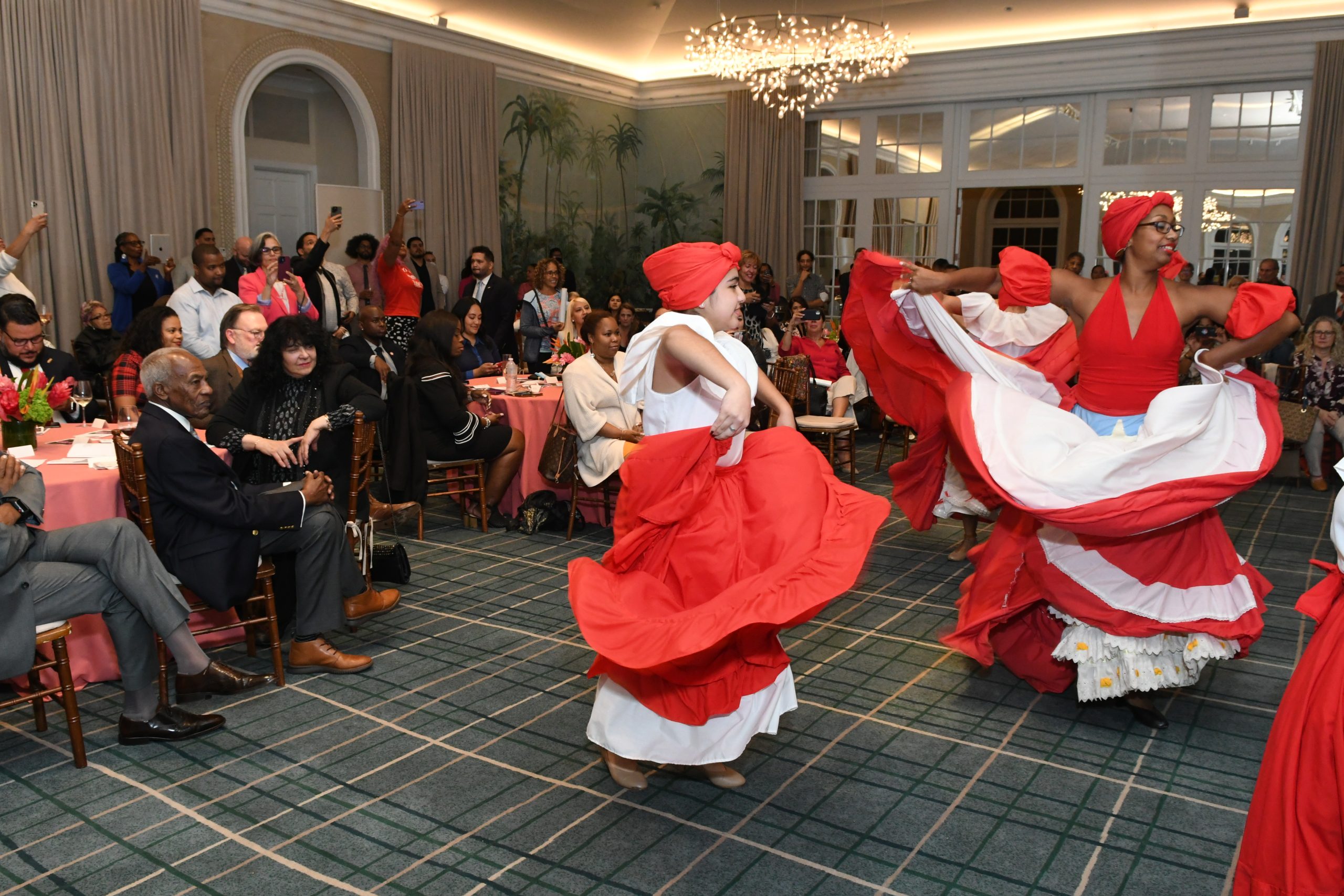 Women in red and white dresses spin in a dance for entertained visitors