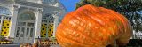Photo of a bright orange multi-hundred pound pumpkin on a crate in front of the Conservatory