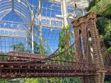 A model bridge made of plant material with a model train zipping across