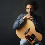 Photo of musician Louis Apollon with a guitar on his lap