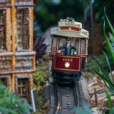 A red model train with a conductor in the front