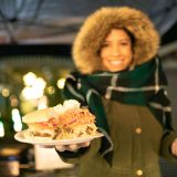 A woman handing over a sandwich