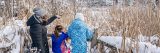 A parent and two children look out over a snowy landscape