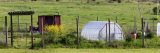 A farm with greenhouse and red shed on it