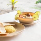 Plates of food on a sunny table alongside a beachscape