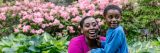 Parent and child smiling in front of pink flowers
