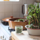 Freshly cut plant stems sit tied in a bowl of water, ready for cooking