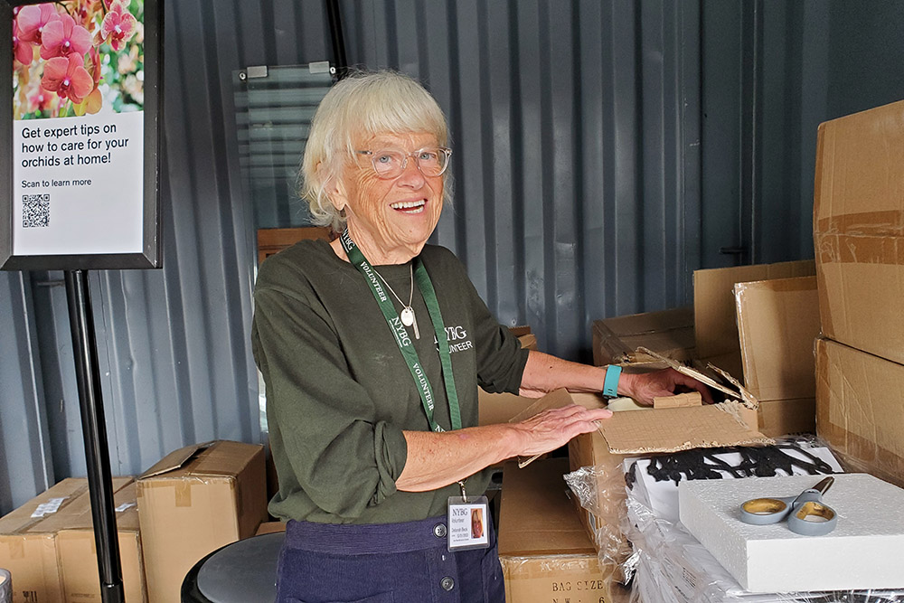 A woman in a green shirt organizes items in boxes during a day at the Garden