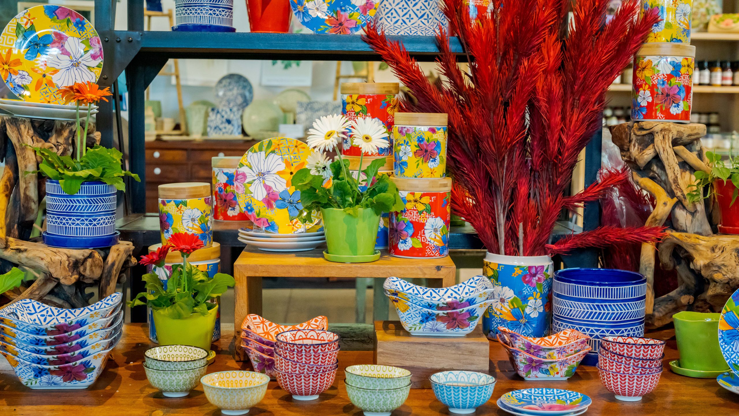 selection of brightly colored floral bowls, plates, and jars in blues, reds and yellows