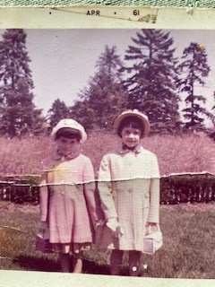 An antique photo of two little girls posing in a garden setting, labeled "April 1961"
