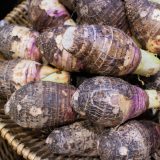 Basket of purple taro rough rounded and oval shapped root vegetable.