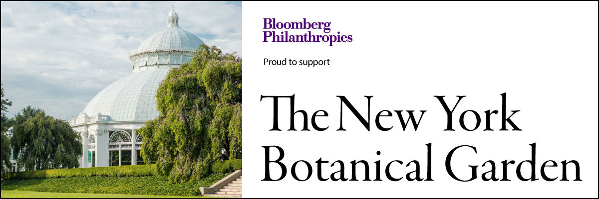 green trees and lawn in front of white conservatory building logo Bloomberg philanthropies proud to support the New York botanical garden