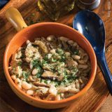 Mushroom soup in an organge bowl on a wooden cutting board