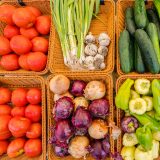 Farmers Market tomatoes, scallions, garlic, red onion, green peppers and cucumbers in woven baskets