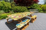 A picnic table painted yellow with illustrations of violets, roses, and wildflowers.