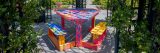 A colorful painted picnic table sits underneath a rosy pergola outdoors