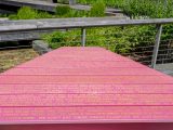 A deep red picnic table sits outdoors, covered in words that tell a love story