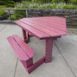 A deep red picnic table sits outdoors, covered in words that tell a love story