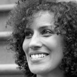 A black and white photo of a woman with curly hair posing for a photo