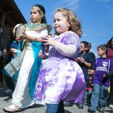 two young children in princess costumes marching in a parade with instruments