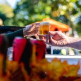 two hands holing a small jug of beer in front of fall foliage