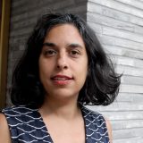 A photo of a woman with mid-length black hair and a black shirt posing for a photo