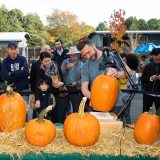 Adam Bierton carving a pumpkin in front of a crowd of people