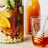 A collection of fruits, honey, and other ingredients steeping in jars