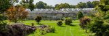 exterior image of Nolen Greenhouses in summer with vibrant green trees and bushes in front of the building