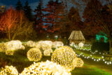 A person off in the distance walks along a path lit on either side with enormous, glowing balls of light.