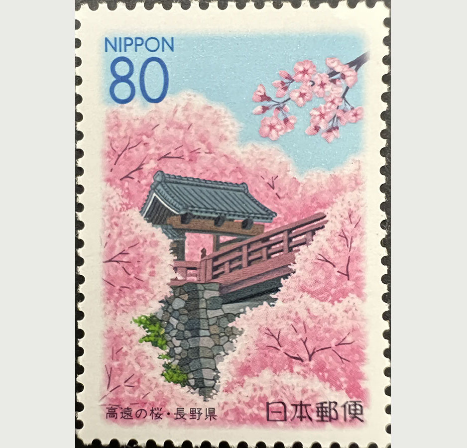 A postage stamp depicting a classical wooden Japanese building among blooming pink cherry blossoms