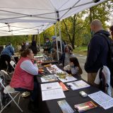 two children at a table with NYBG pamphlets and green and red leaves on it