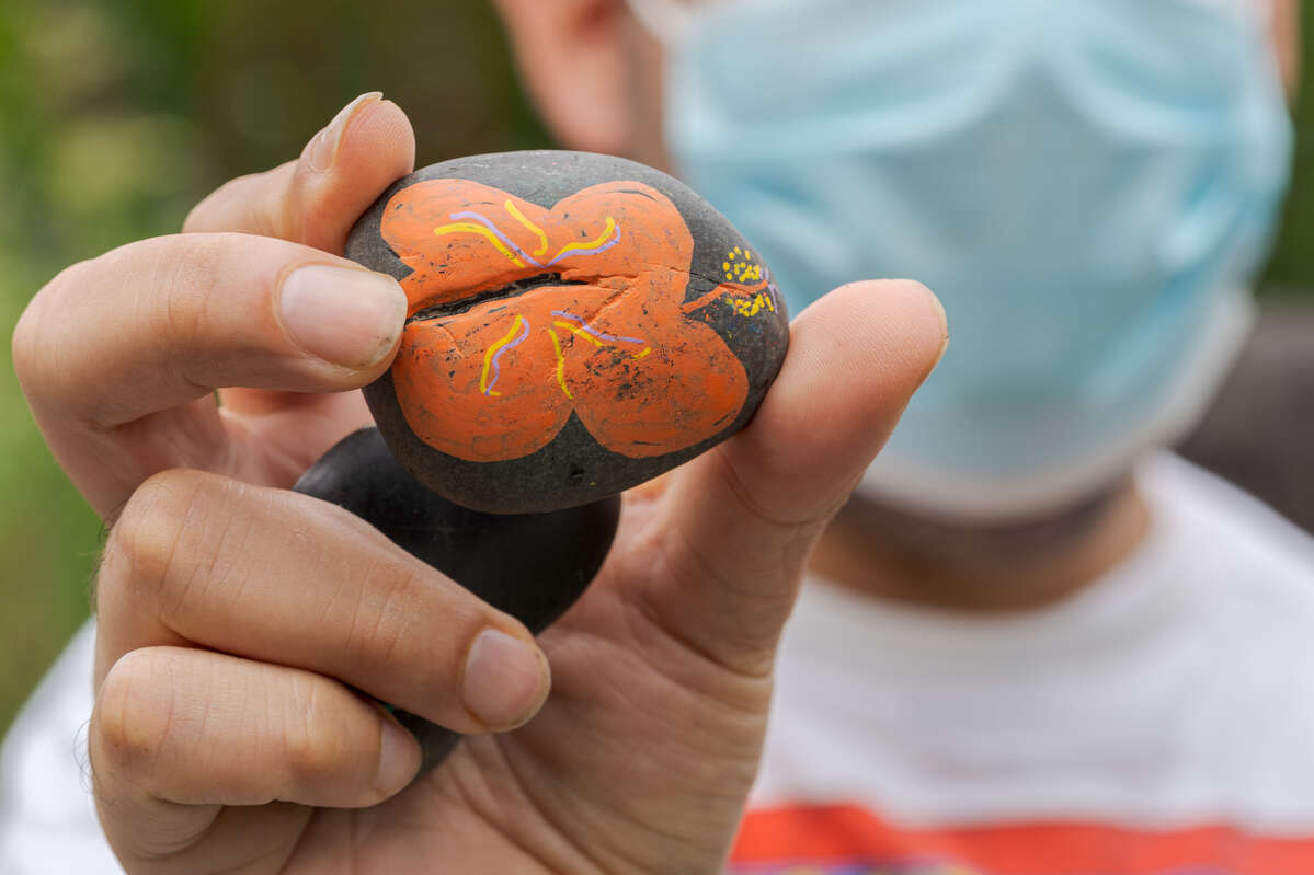 A painted gray rock with an orange flower on it