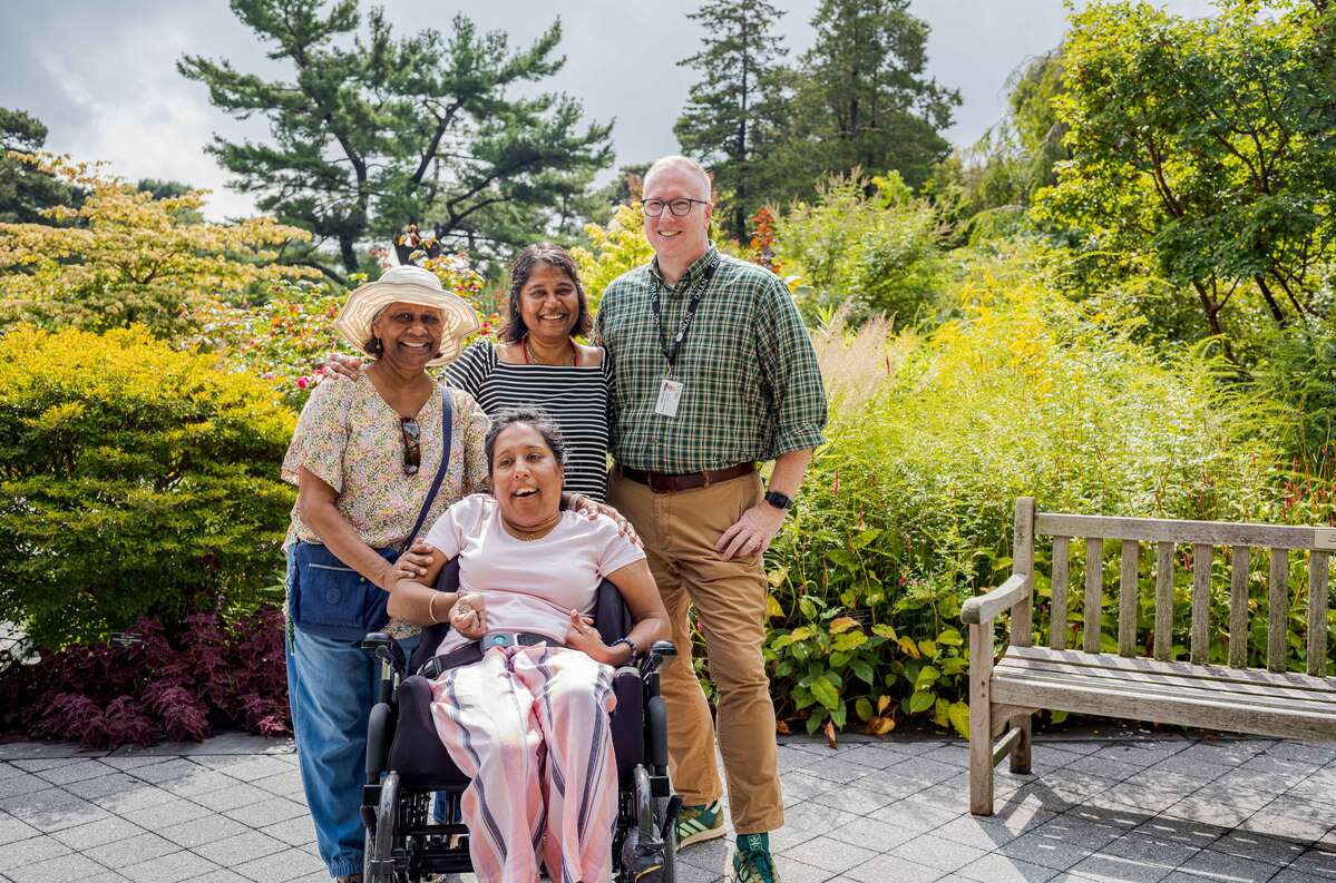 Four people pose happily for a photo in a green garden